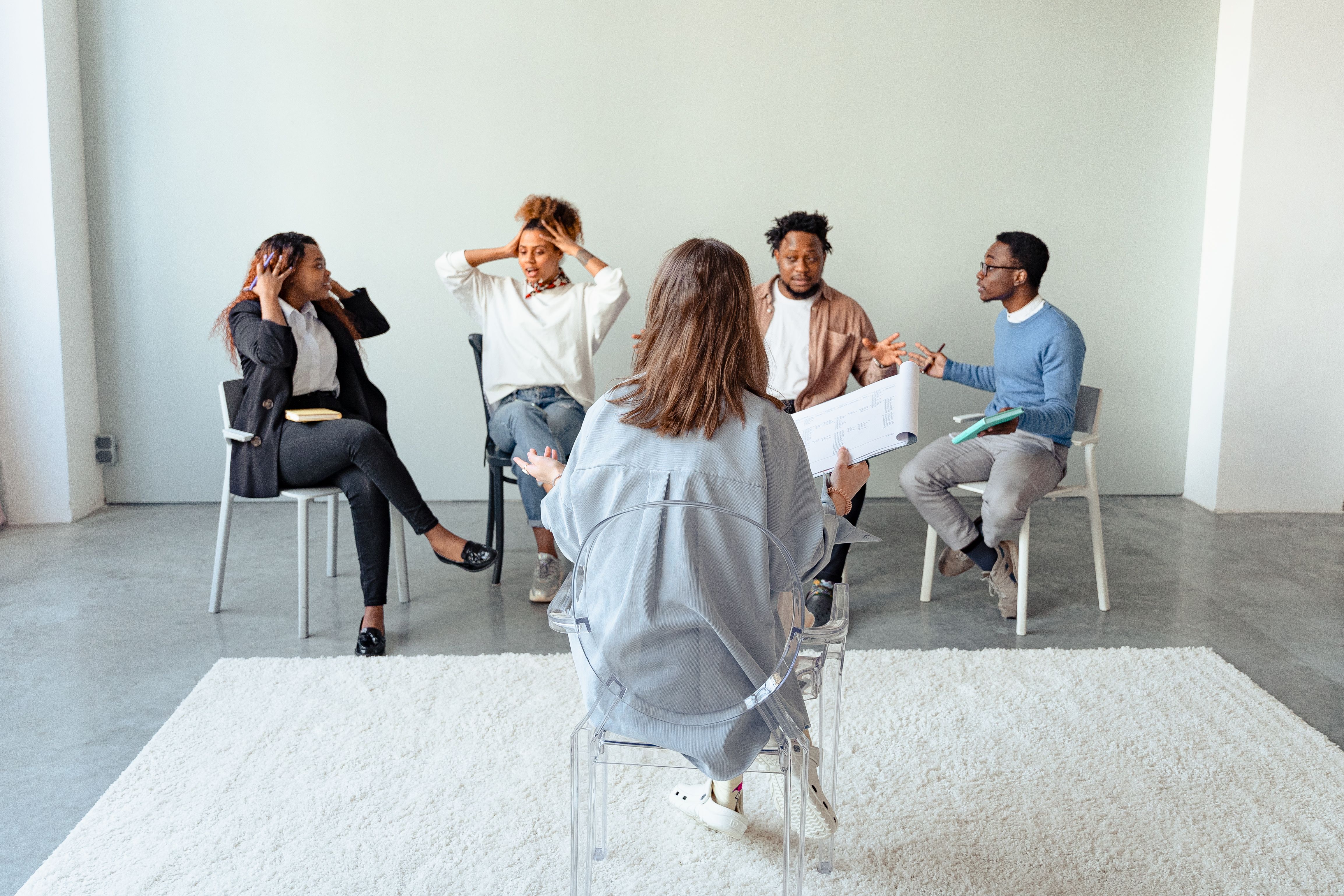 A diverse group of people of color sitting together in a supportive group therapy session