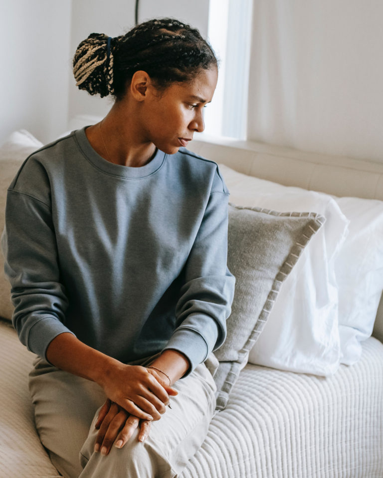 A Black woman sitting quietly, reflecting — representing adults seeking mental health care