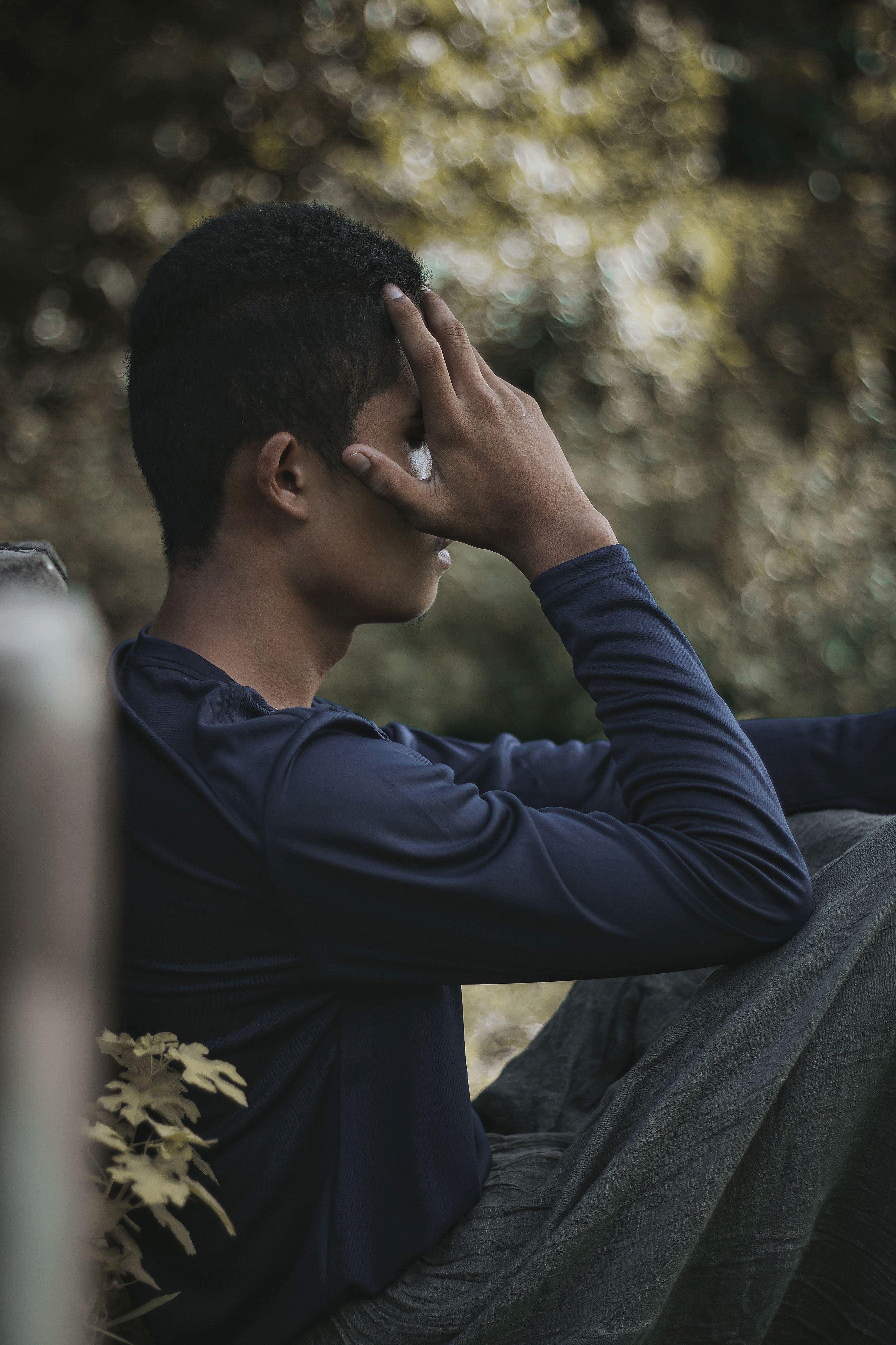 A young Black teen resting his head on his hand, representing teens who may benefit from mental health support