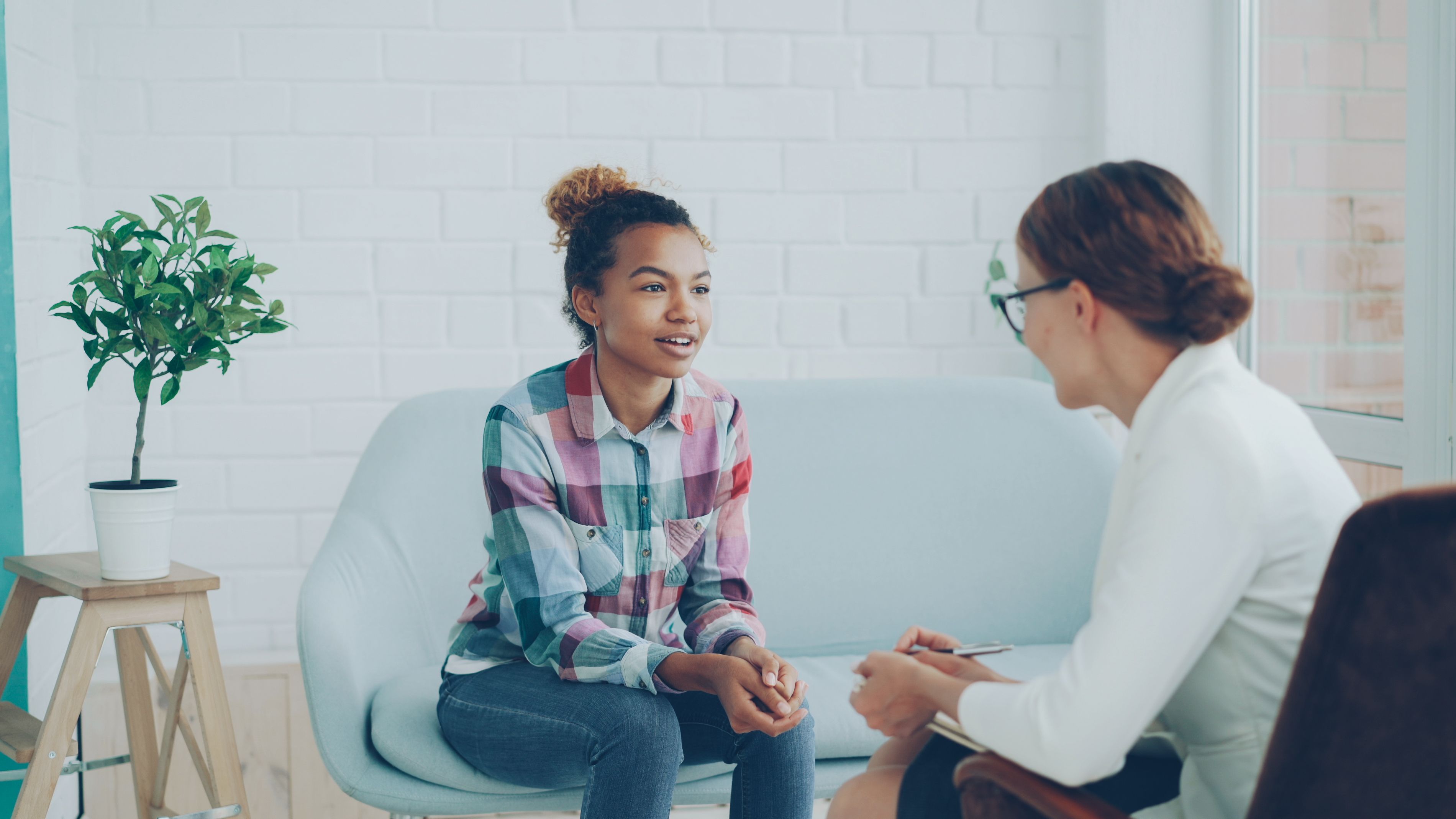 A Black teen smiling with a caring provider, representing compassionate teen mental health care